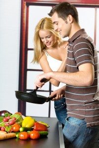 Young attractive happy smiling couple playfully cooking at kitch