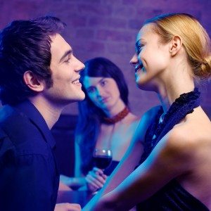 Young couple and woman looking at them at club