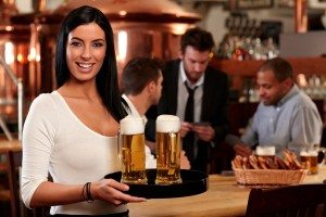 Happy young waitress with beer