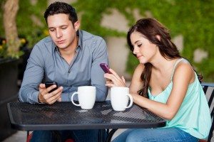 Ppassing the time by using their cell phones on a bad date