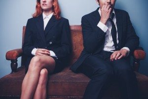 Nervous businessman sitting next to confident businesswoman
