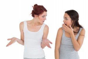 Unhappy young female friends having an argument over white background
