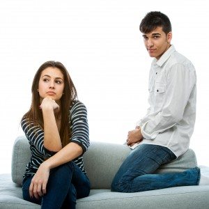 Teen couple with long faces after quarrel.