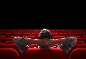 one man sitting in empty cinema or theater auditorium