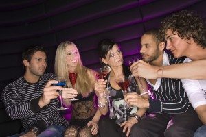 Five friends sitting in a nightclub and toasting martini glasses