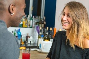 Smiling young couple drinking a cocktail in a bar.