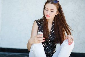 Young woman writes an SMS to your mobile phone