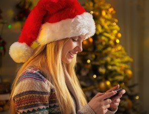 Profile portrait of happy teenager girl in santa hat writing sms