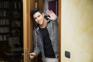 Smiling young man getting out of door waving at the camera