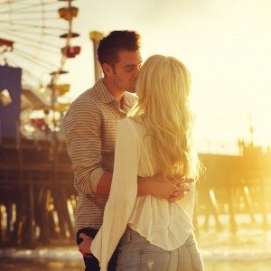young romantic couple kissing in front of sunset in santa monica