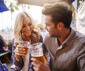 romantic couple drinking beer in plastic cups at outdoor bar