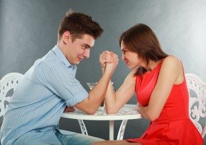 Young happy couple challenge fighting in arm-wrestling at table