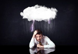 Depressed businessman sitting under a cloud