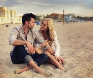 couple sitting in the sand and talking on beach