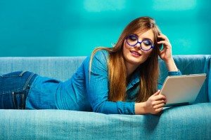 woman with tablet relaxing on couch blue color