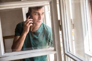 Man standing by the window and using smart phone