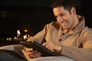 Man using tablet in front of fire at home