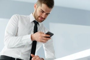 Business Man Reading Something on the Screen of His Cell Phone