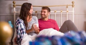 Young Couple Relaxing In Bed With Hot Drink