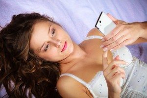 Lying girl holding smartphone.