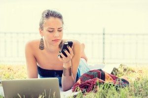sad skeptical unhappy serious woman texting on phone outdoors in park